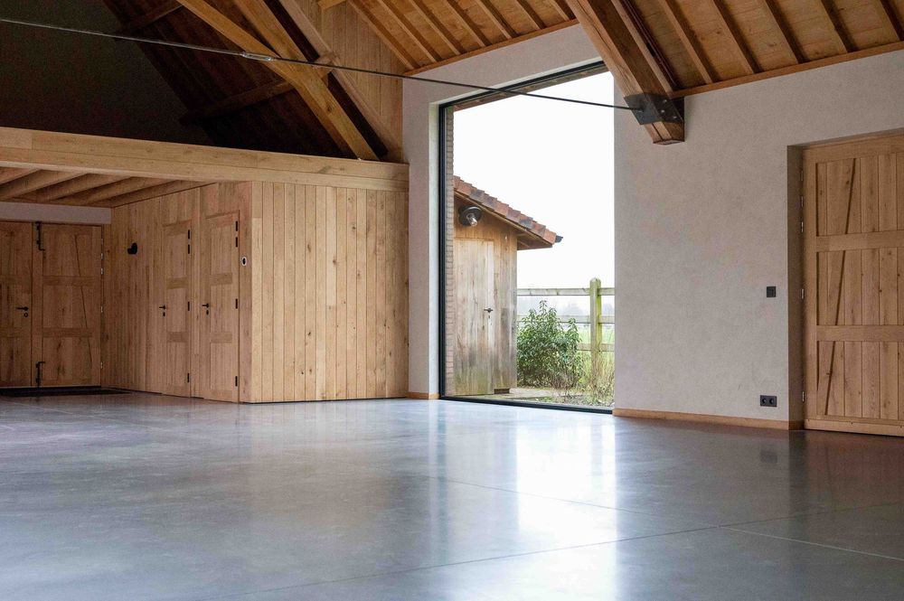 Spacious loft area with exposed wooden beams and polished concrete flooring.