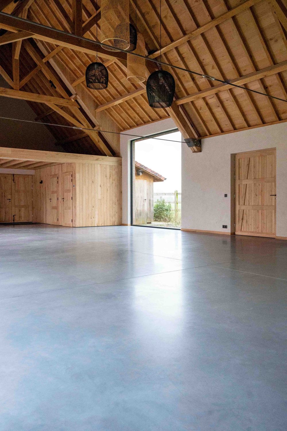 Open attic space featuring timber roof trusses and smooth gray flooring.
