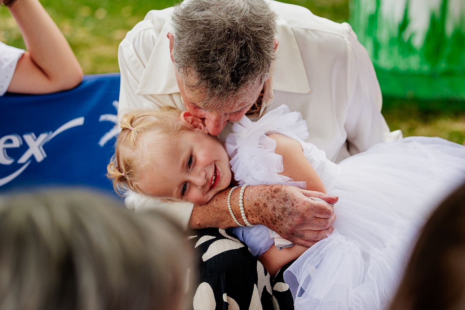 A tender outdoor wedding moment of a couple in formal attire sharing a loving kiss.