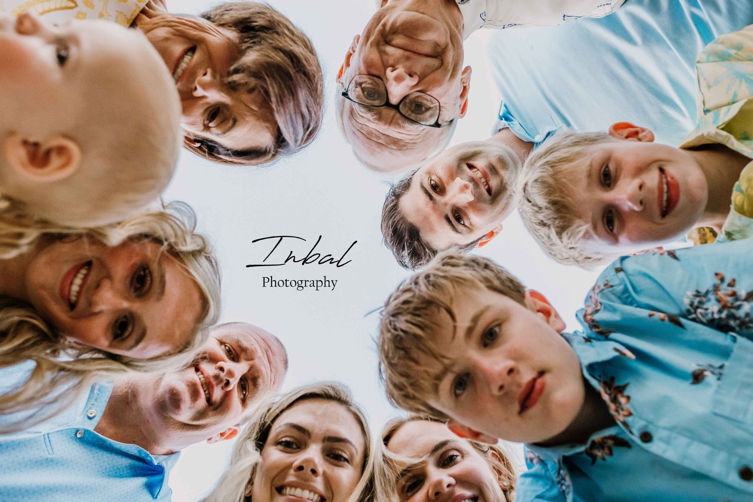 Fun photo of the whole family putting their heads together in a circle and looking down at the camera, which is placed on the floor.