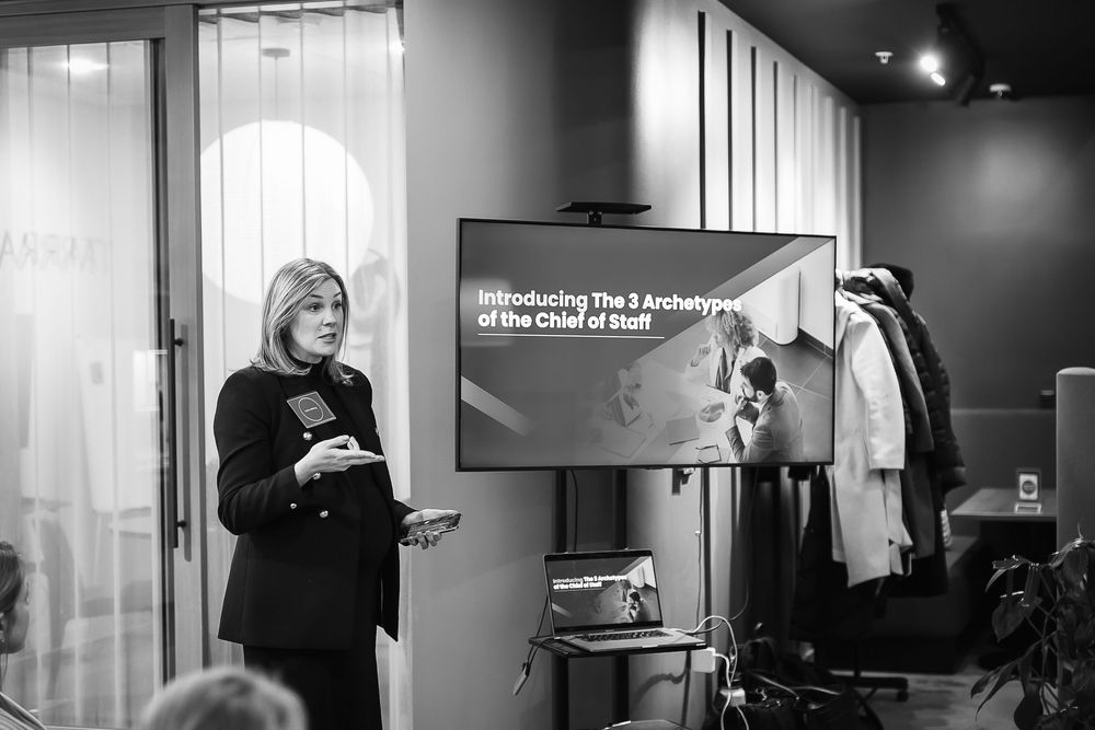 A professional woman speaks to a crowd while giving a presentation in black and white professional image