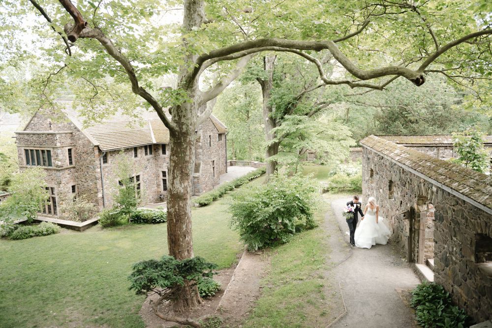 A scenic stone pathway leads through lush gardens at a historic stone building venue on a spring day.
