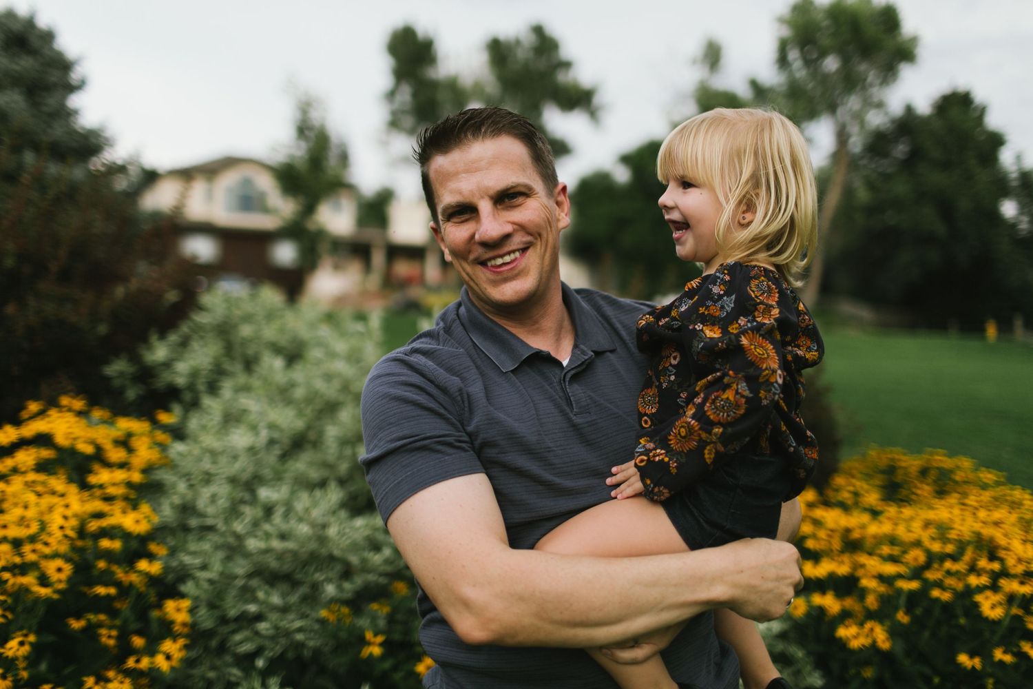 A joyful moment captured outdoors with yellow wildflowers blooming in the background.