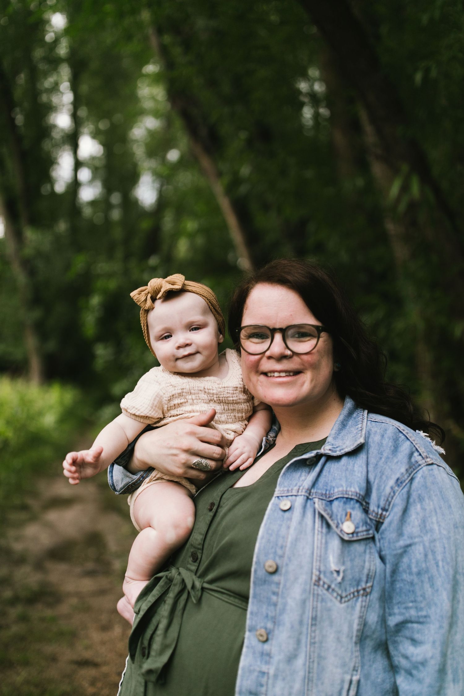 A parent and baby share a happy moment together in a wooded setting.