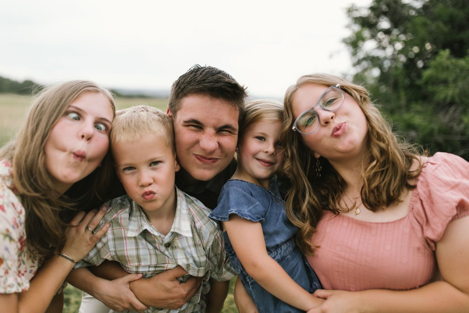 A playful family photo with everyone making silly faces outdoors.