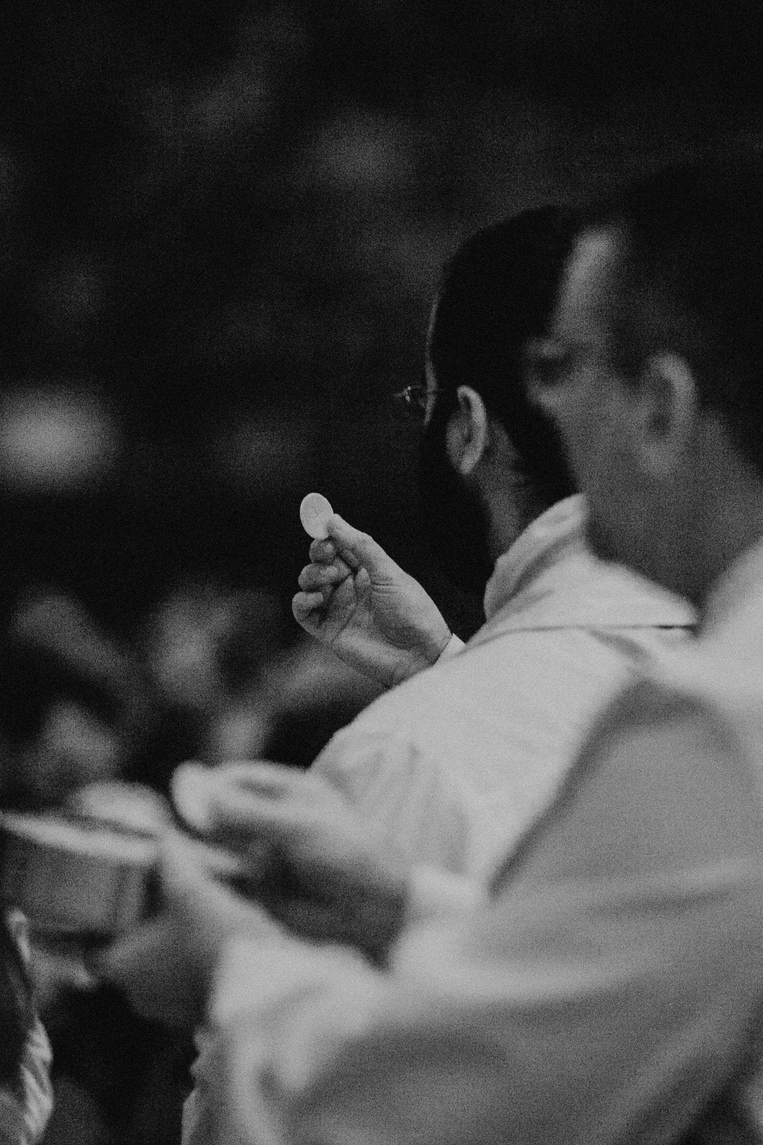 Black and white profile view of person holding communion wafer during service.