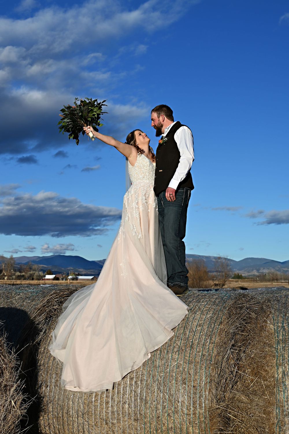 Bride and Groom standing atop a round bail flowers raised in excitement
Ranch style wedding portraits