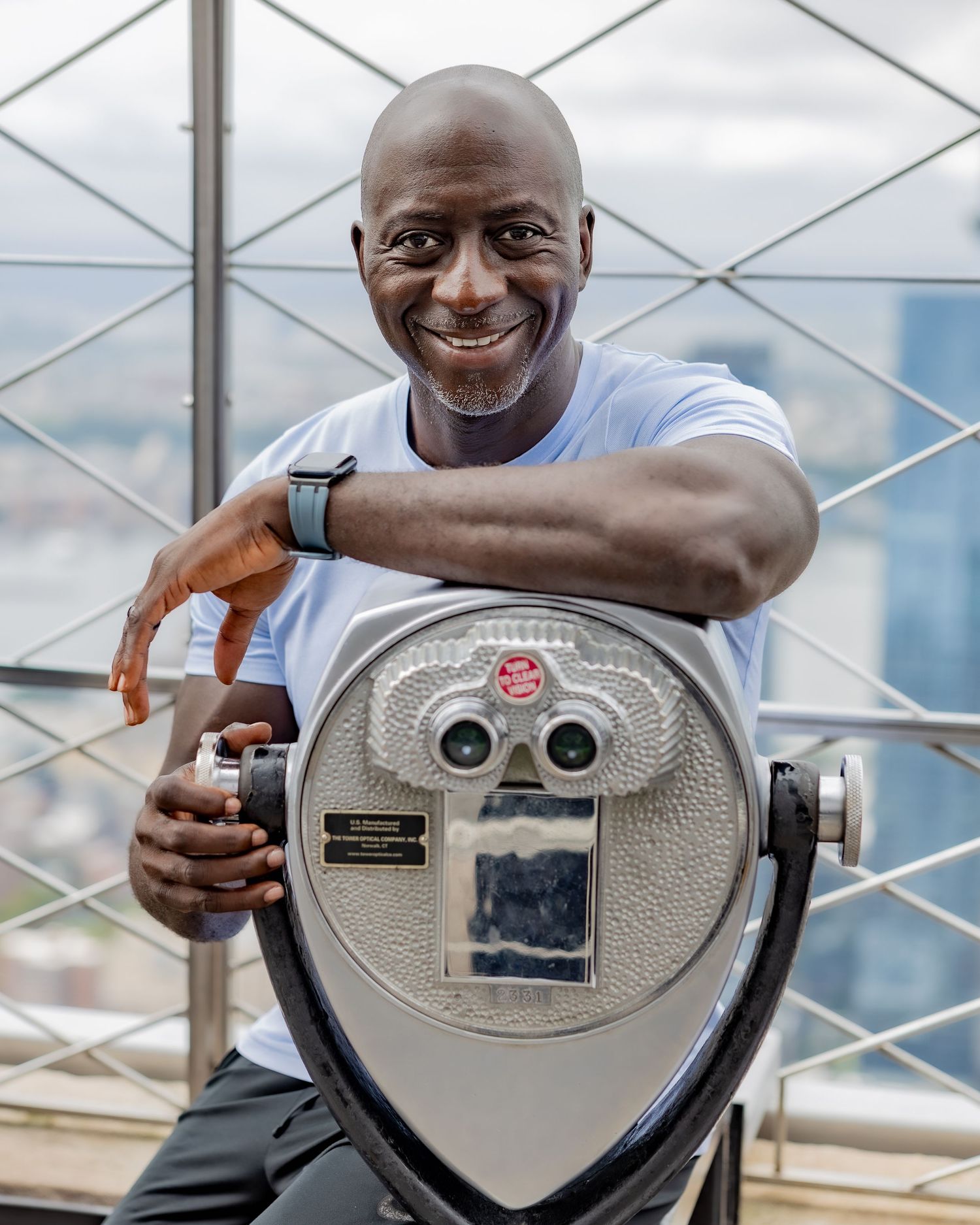 A cheerful pose with a tourist viewfinder on an observation deck with city views.
