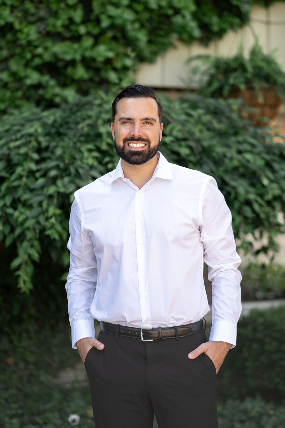 Professional portrait series of person in white button-down shirt and dark pants against green foliage backdrop outdoors.