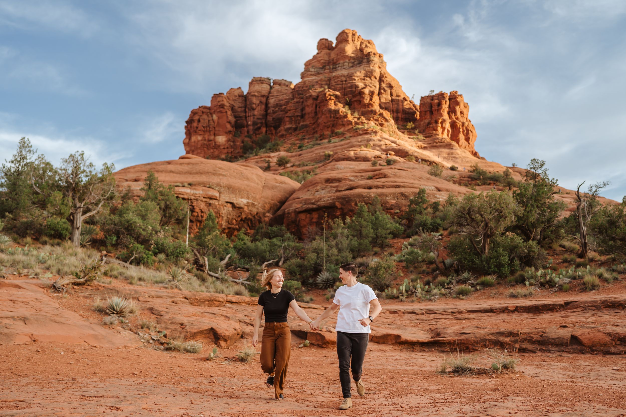 A couple runs across the Sedona red rocks during their engagement photo session