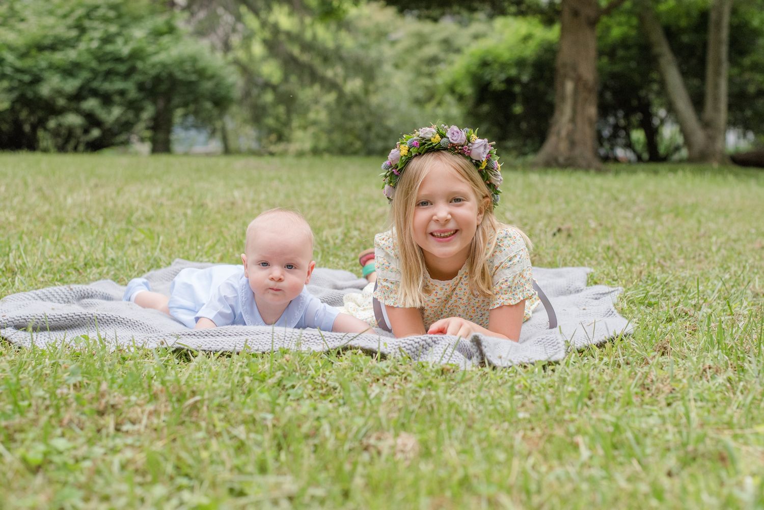 Full family photography session in Northern Virginia, girl with flower crown laughs next to infant brother on a blanket in the grass