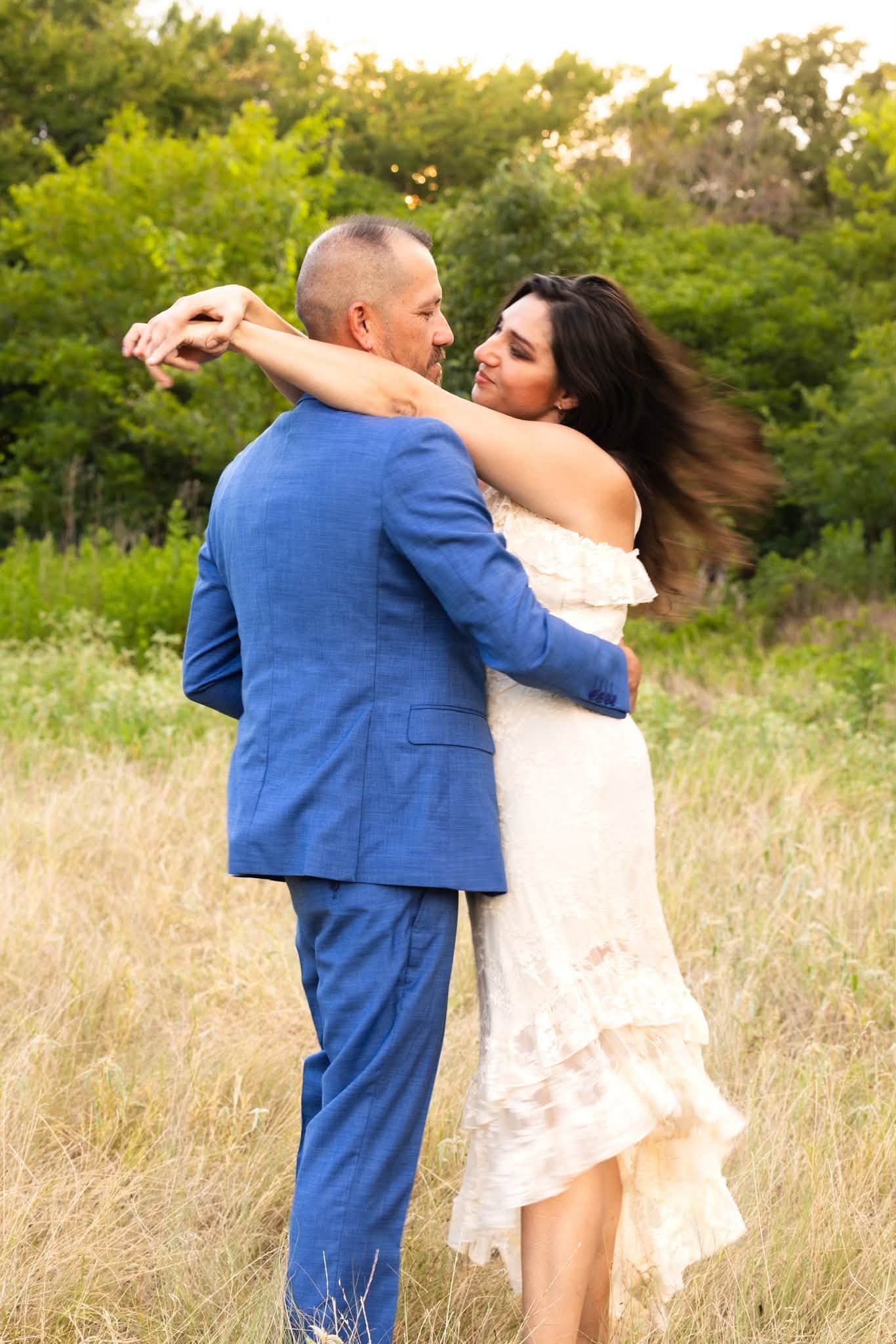 Romantic couple sharing an intimate moment, foreheads touching, man in blue suit, warm golden sunlight background.