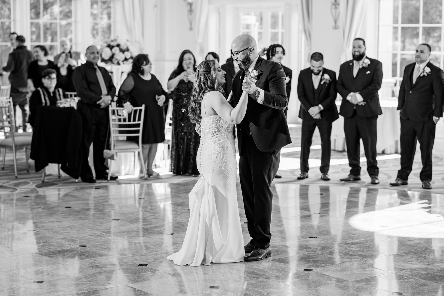 Black and white photo of bride and groom sharing first dance at elegant wedding reception with guests watching at the Aria in Prospect, CT