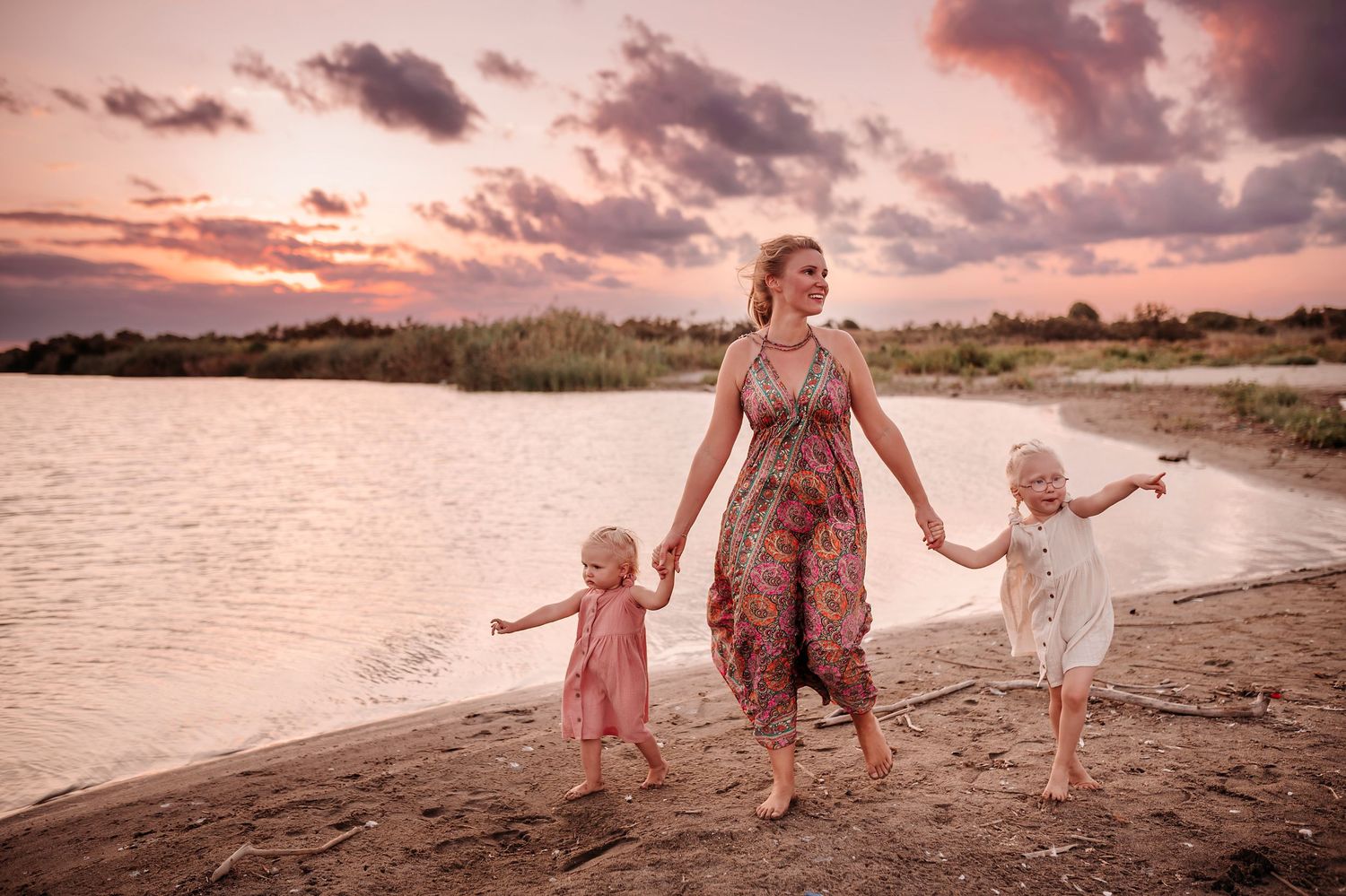 Mother and two children walking a wild beach at the Simeto river mouth near Catania at sunset
