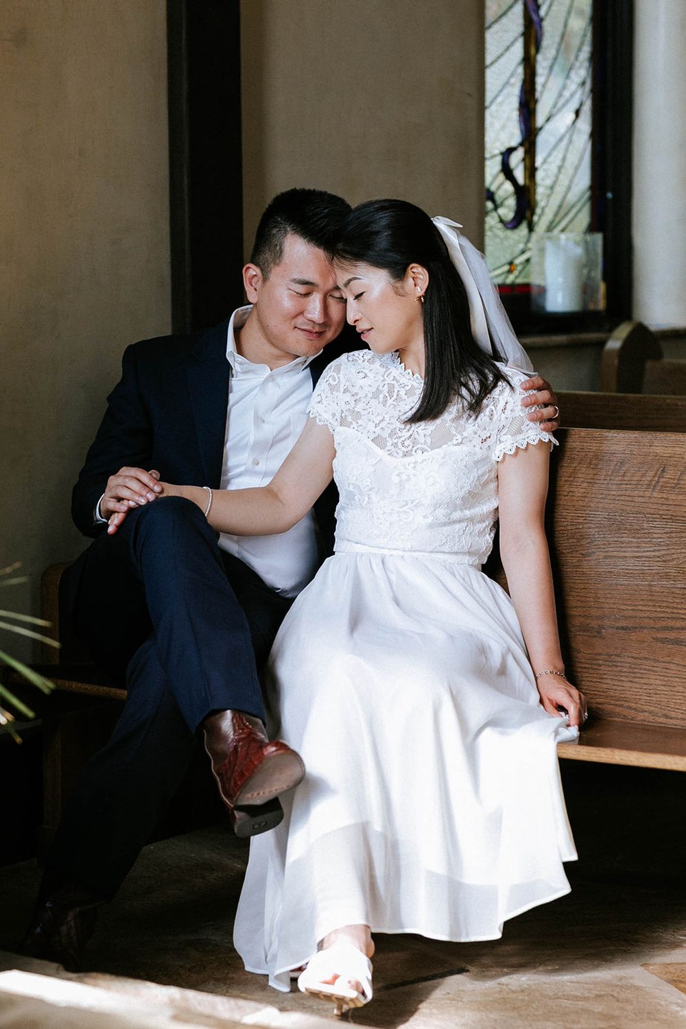 Bride and groom cuddled together on a wooden bench at their intimate chapel elopement in Fayetteville, Arkansas