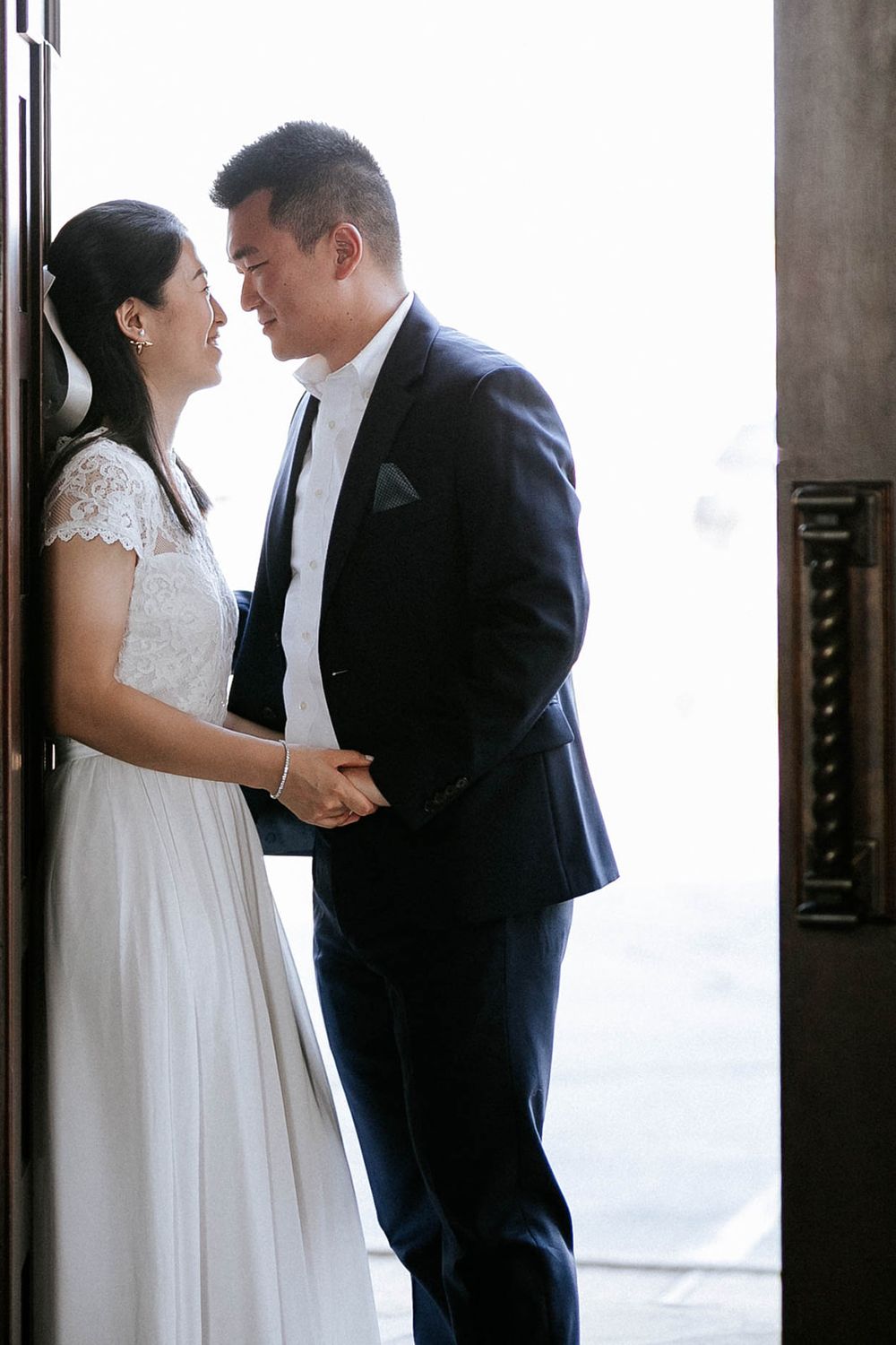 Bride and groom sharing a tender moment in a sunlit chapel doorway at their Fayetteville, Arkansas elopement