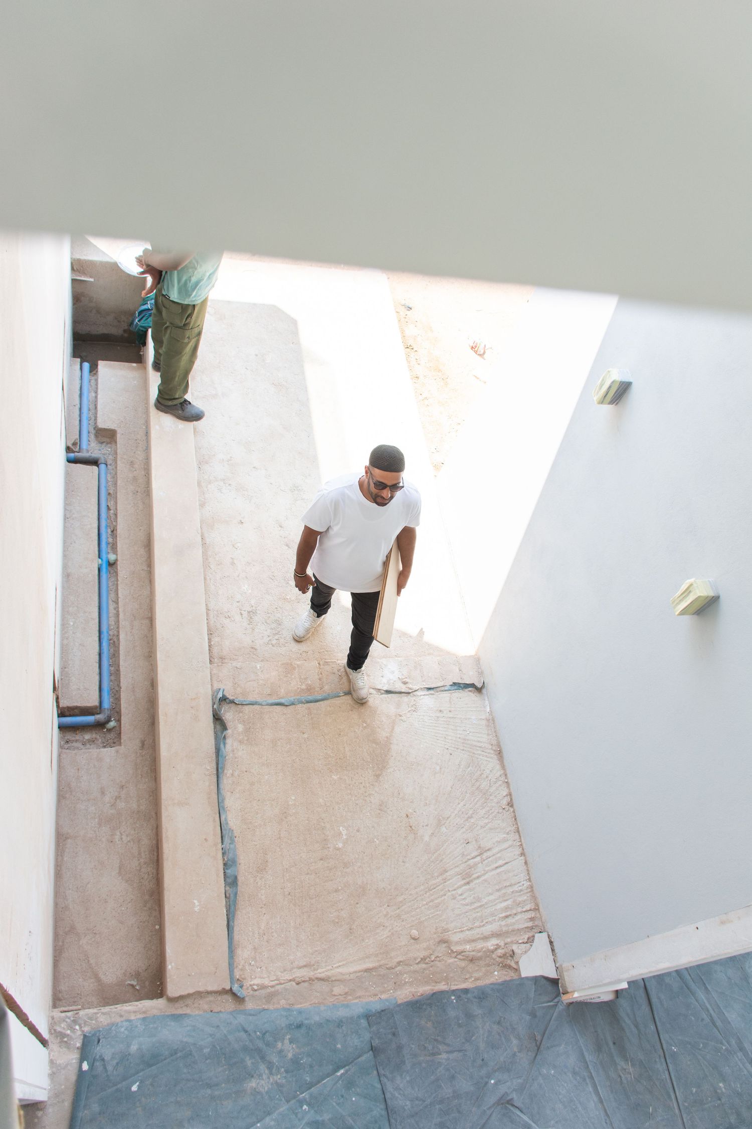 Muhammed, an interior designer, walking through a building under renovation with exposed walls and pipes.
