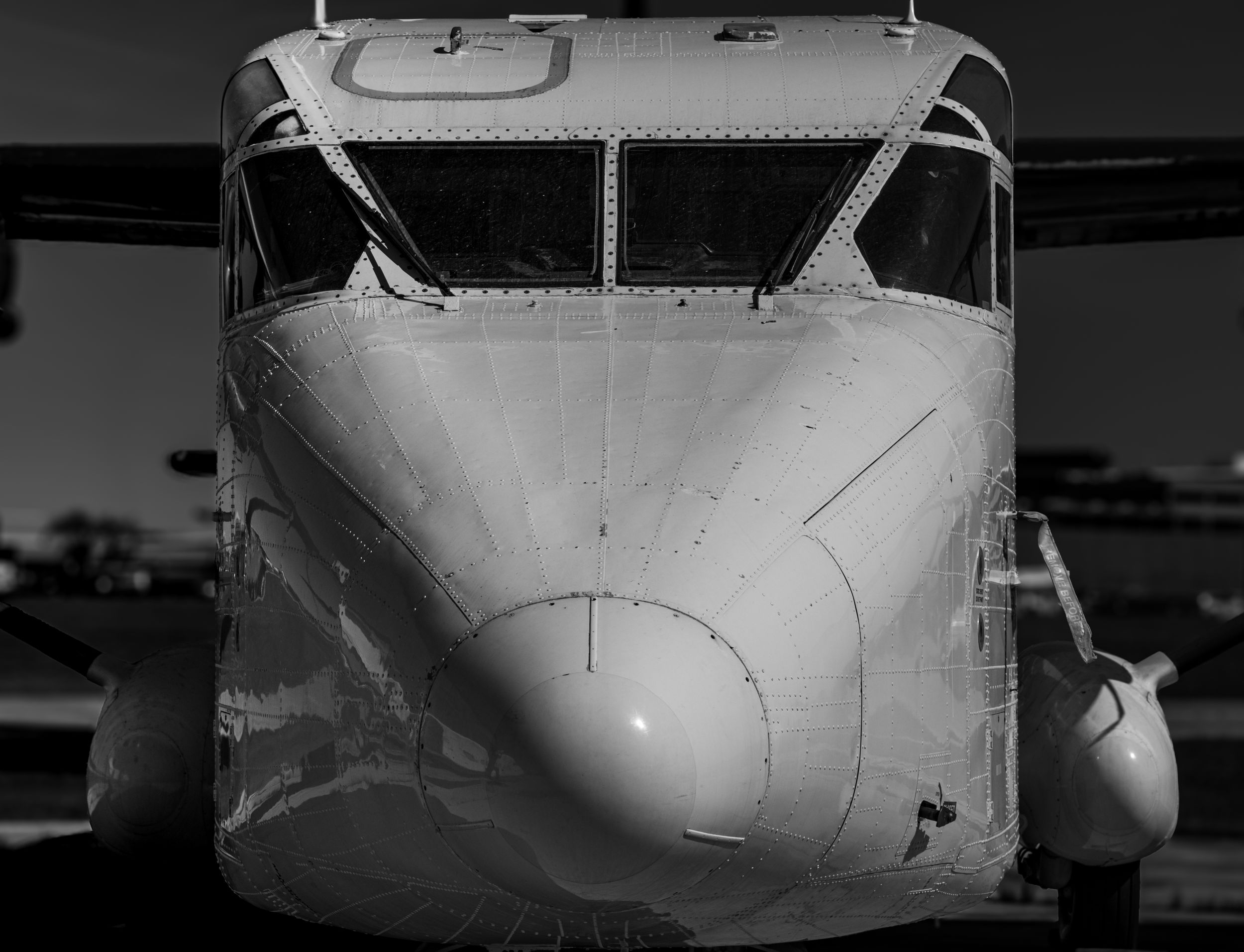 Black and white close-up front view of a vintage cargo aircraft nose and cockpit.