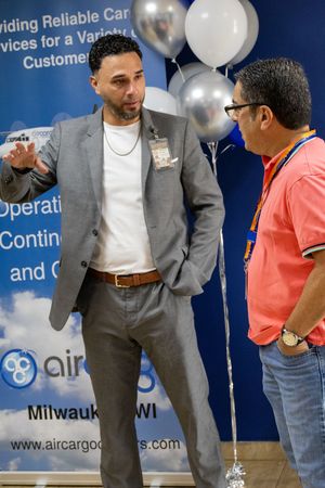 Man in gray suit conversing with colleague at an Air Cargo Carriers Milwaukee WI event.