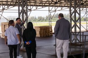 Group of people discussing logistics inside an open warehouse facility.