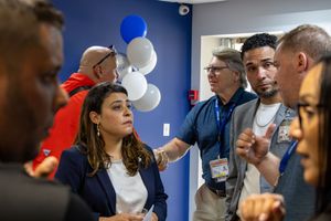 Professionals networking at an Air Cargo Carriers event with blue and white balloons in the background.