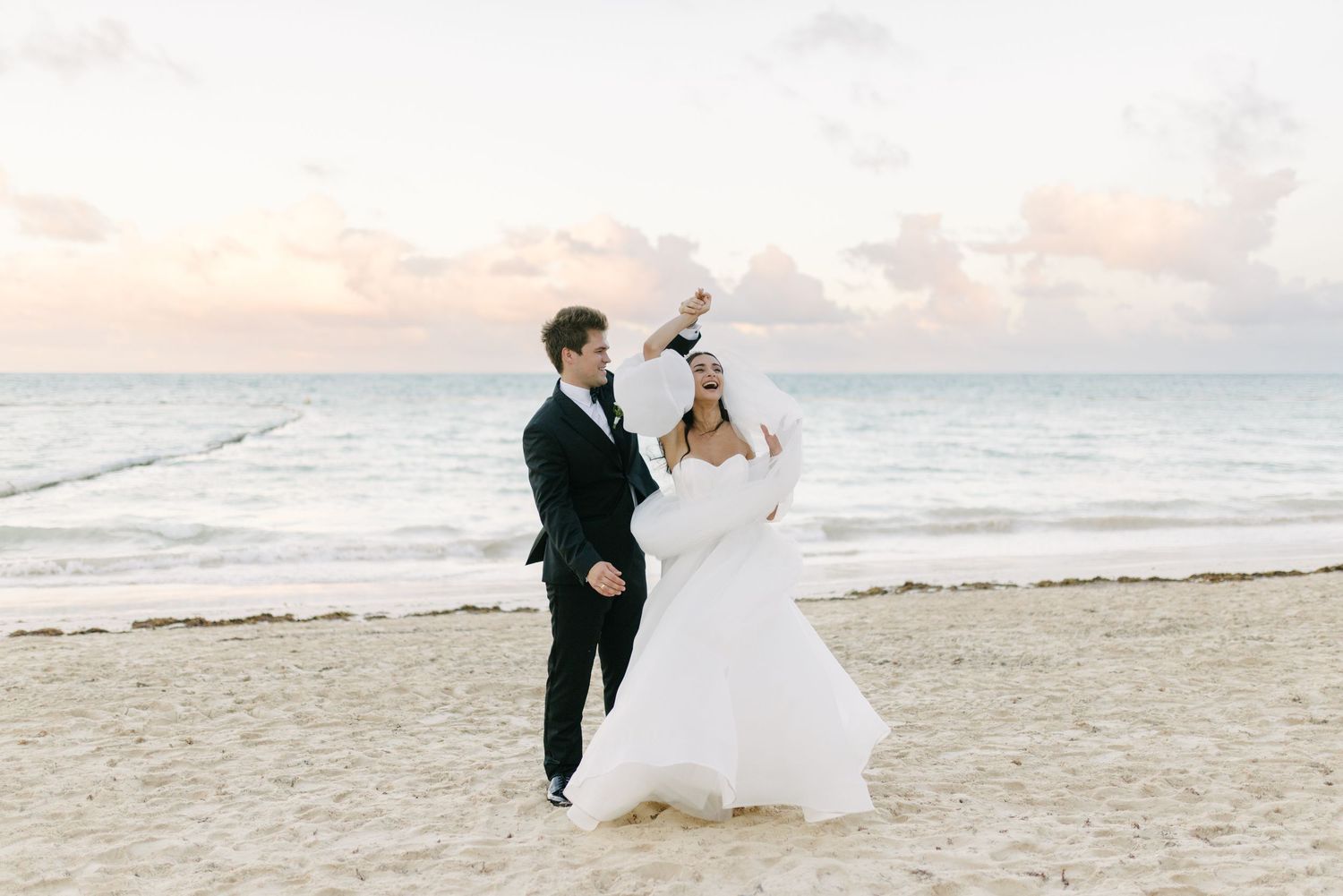 Bride and groom kissing on a sandy lake beach.