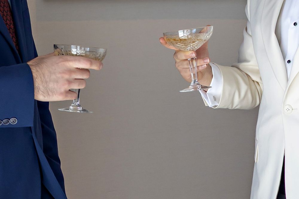 Two people in formal attire toasting with elegant coupe champagne glasses at a celebration.
