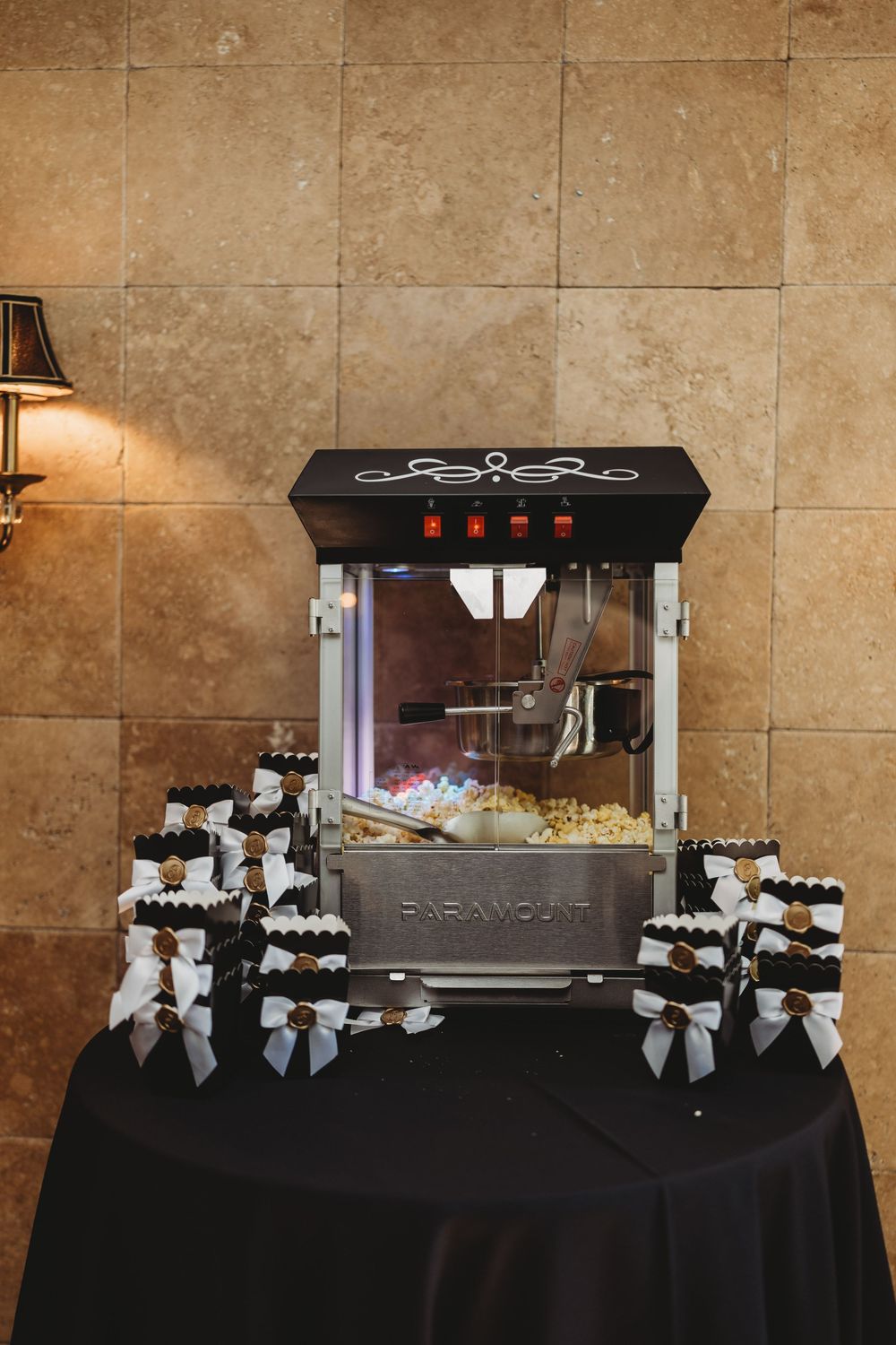 Paramount popcorn machine wedding favor station with black and white bow-tied treat boxes on display.