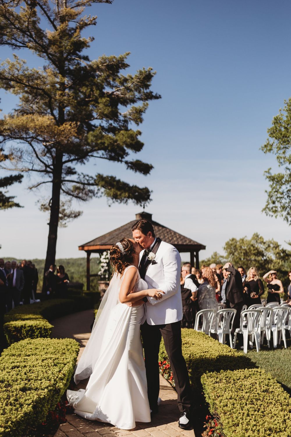 A newlywed couple shares a romantic moment while walking back down the aisle after their outdoor garden ceremony.
