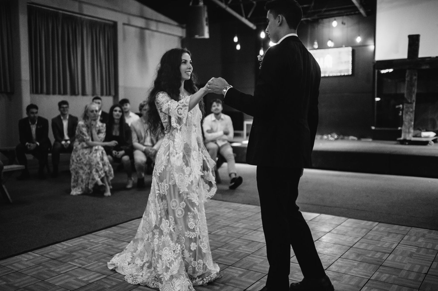 Bride and groom share first dance at wedding reception in black and white photo.