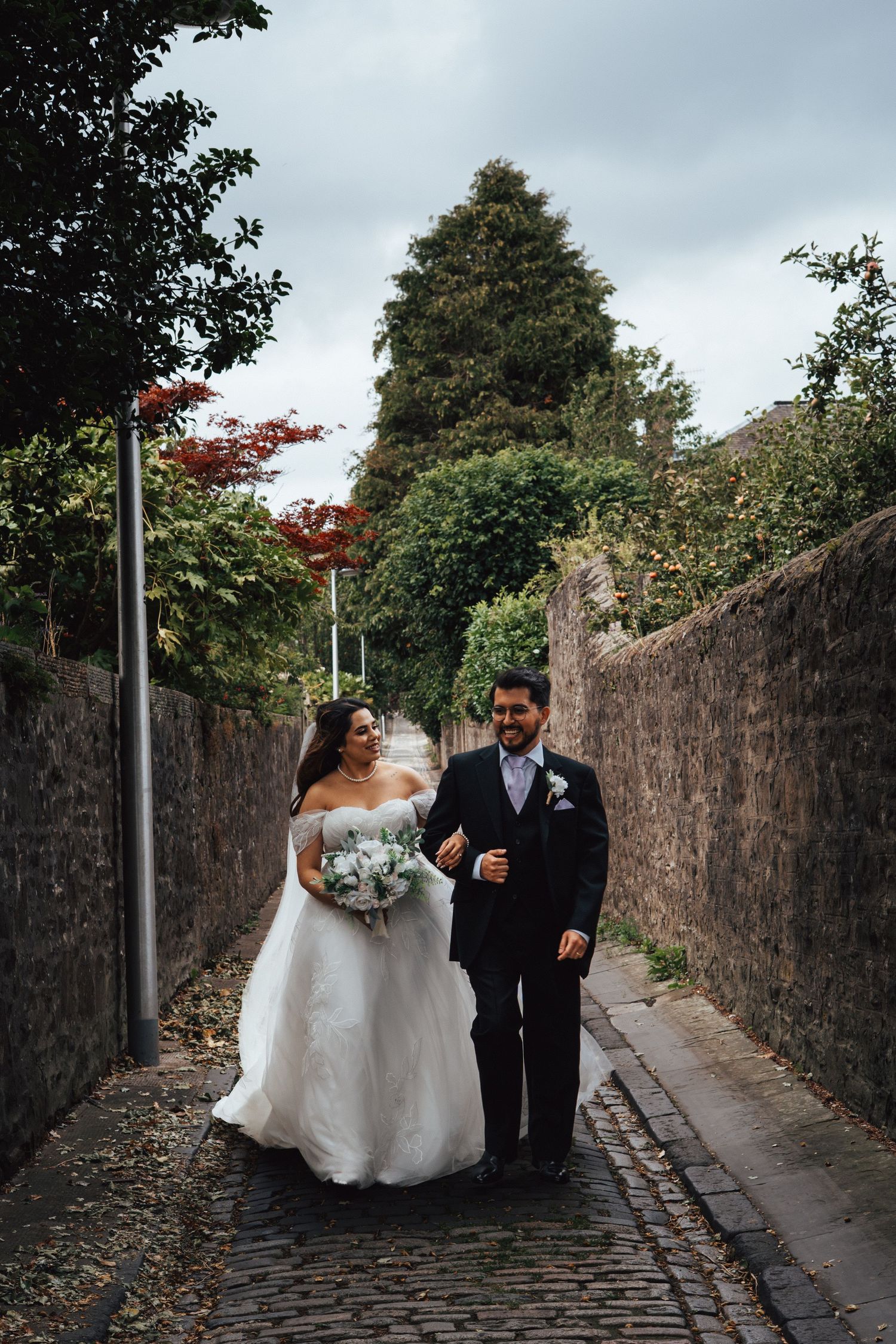 Bride and groom walk down a historic cobbled lane in Scotland, Captured by a Scottish Wedding and elopement photographer
