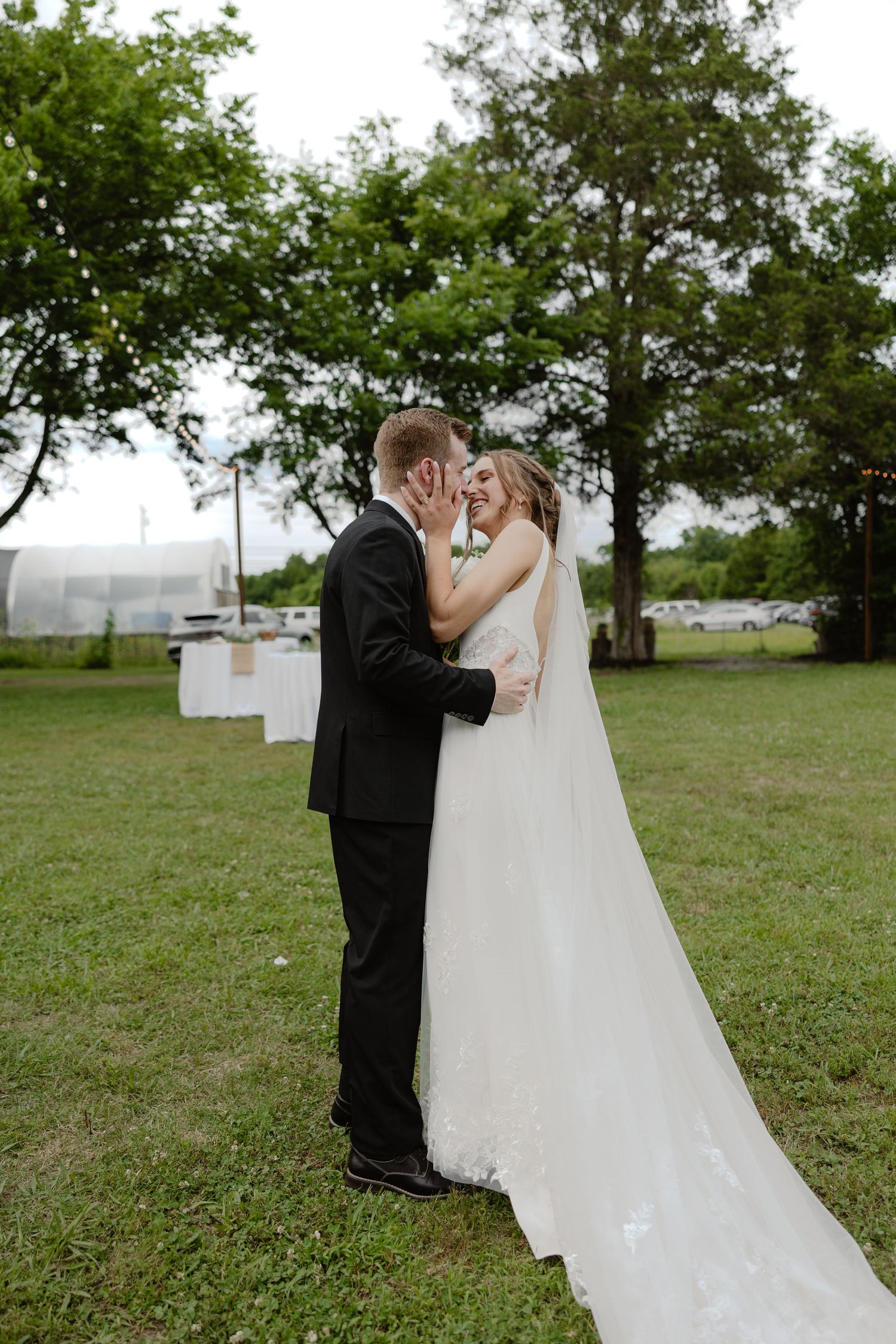 Bride and groom embracing and smiling in outdoor garden wedding setting.