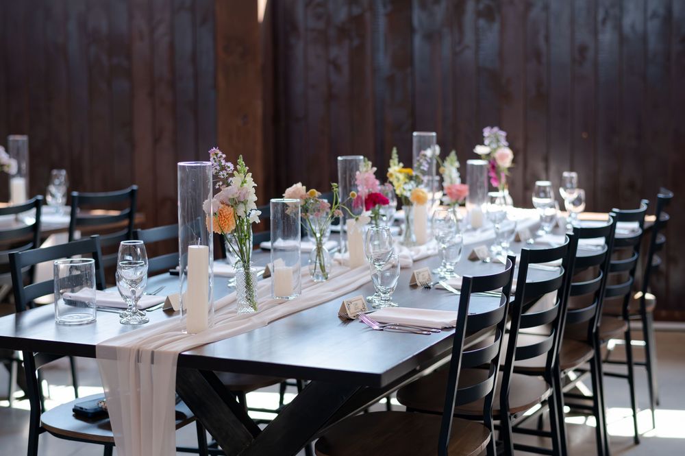 Elegant rustic wedding reception table set with floral centerpieces, candles, and glassware at barn swallow fields in guelph, ontario.