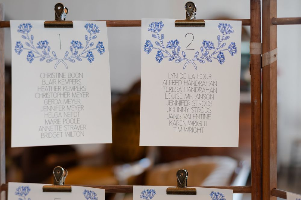 Blue and white floral wedding seating chart cards displayed on wooden clipboards at barn swallow fields in guelph, ontario.