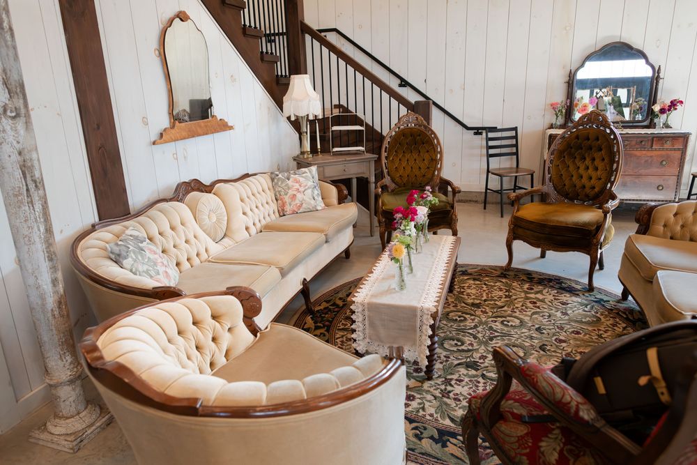Elegant vintage living room with tufted cream sofa, ornate wooden chairs, floral rug at barn swallow fields in guelph, ontario.