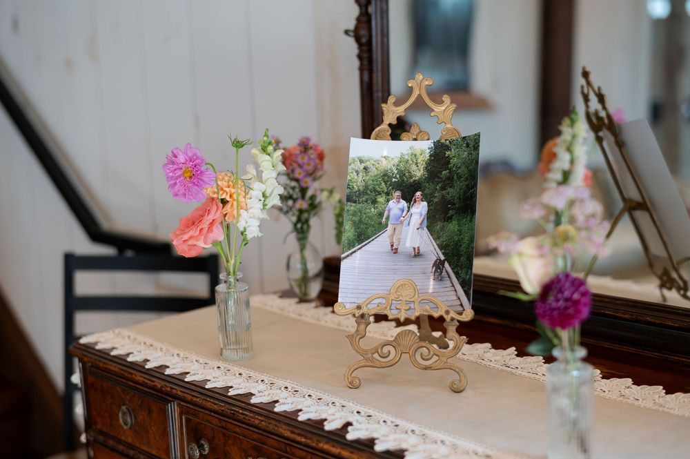 Wedding photo displayed on ornate easel with fresh wildflowers in glass vases at barn swallow fields in guelph, ontario.