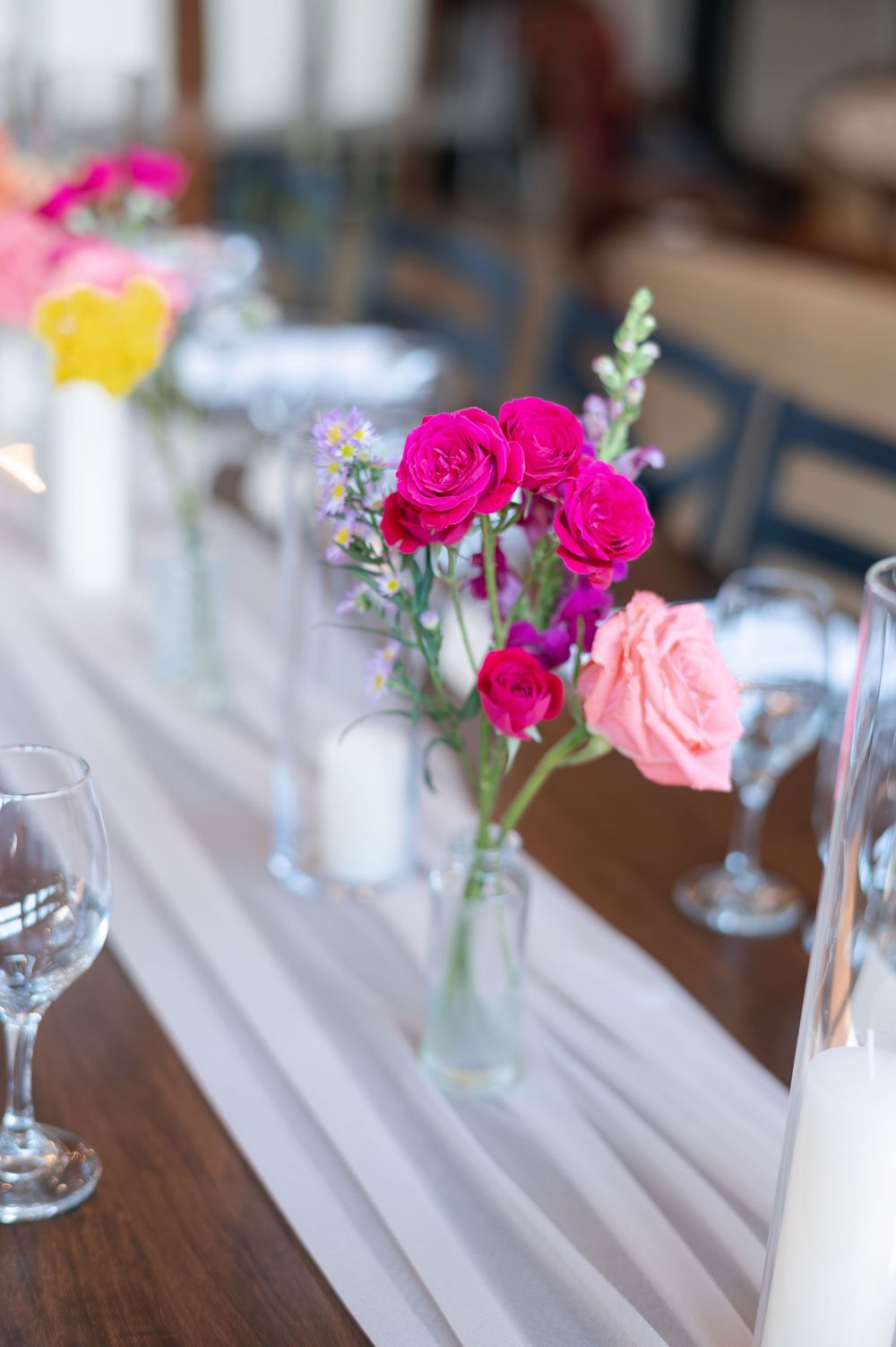 Elegant wedding table centerpiece with vibrant pink roses and colorful wildflowers at barn swallow fields in guelph, ontario.