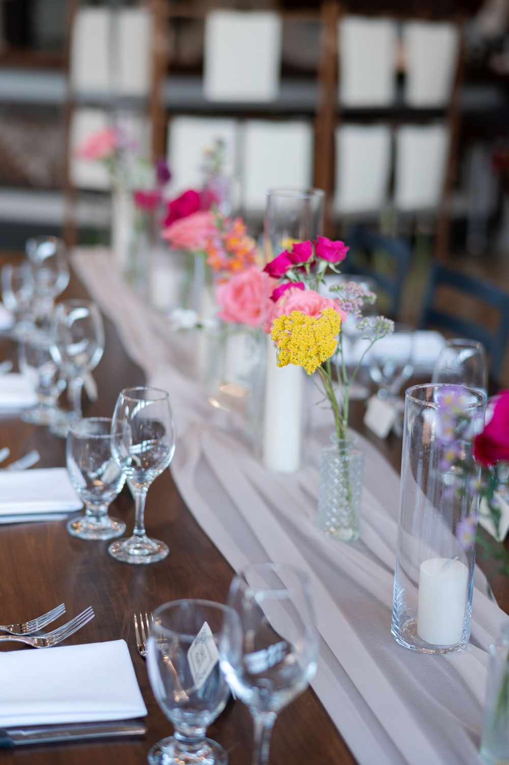 Elegant wedding reception table with colorful pink and yellow floral arrangements at barn swallow fields in guelph, ontario.