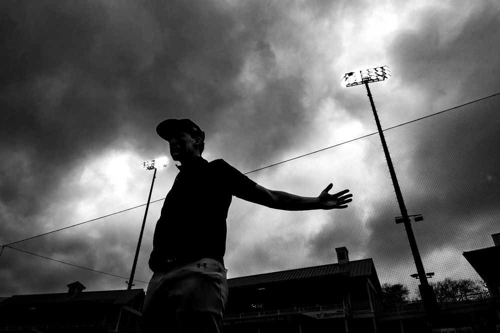 Silhouette of athlete with outstretched arms against dramatic stormy sky at outdoor sports complex.