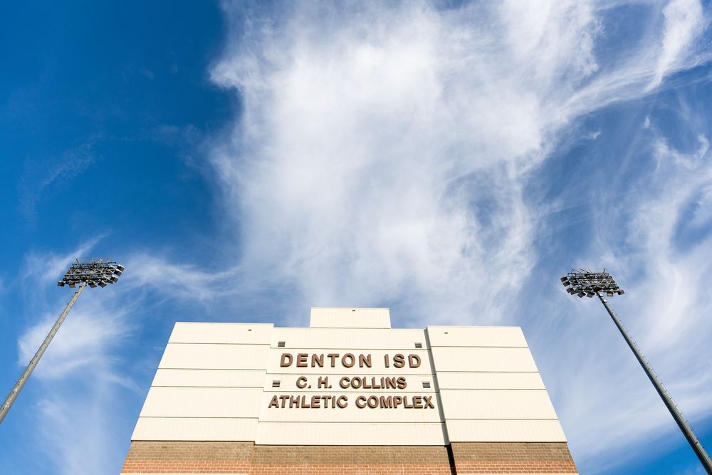 Low angle view of Denton ISD C.H. Collins Athletic Complex signage against blue sky.