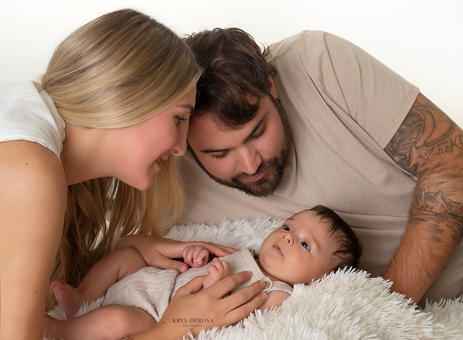 A peaceful newborn baby sleeping curled up on a soft knit blanket, with tiny hands tucked under their chin.