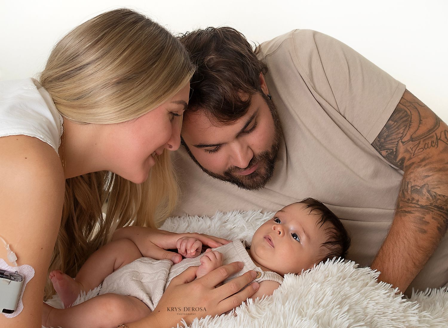 A peaceful newborn baby sleeping curled up on a soft knit blanket, with tiny hands tucked under their chin.