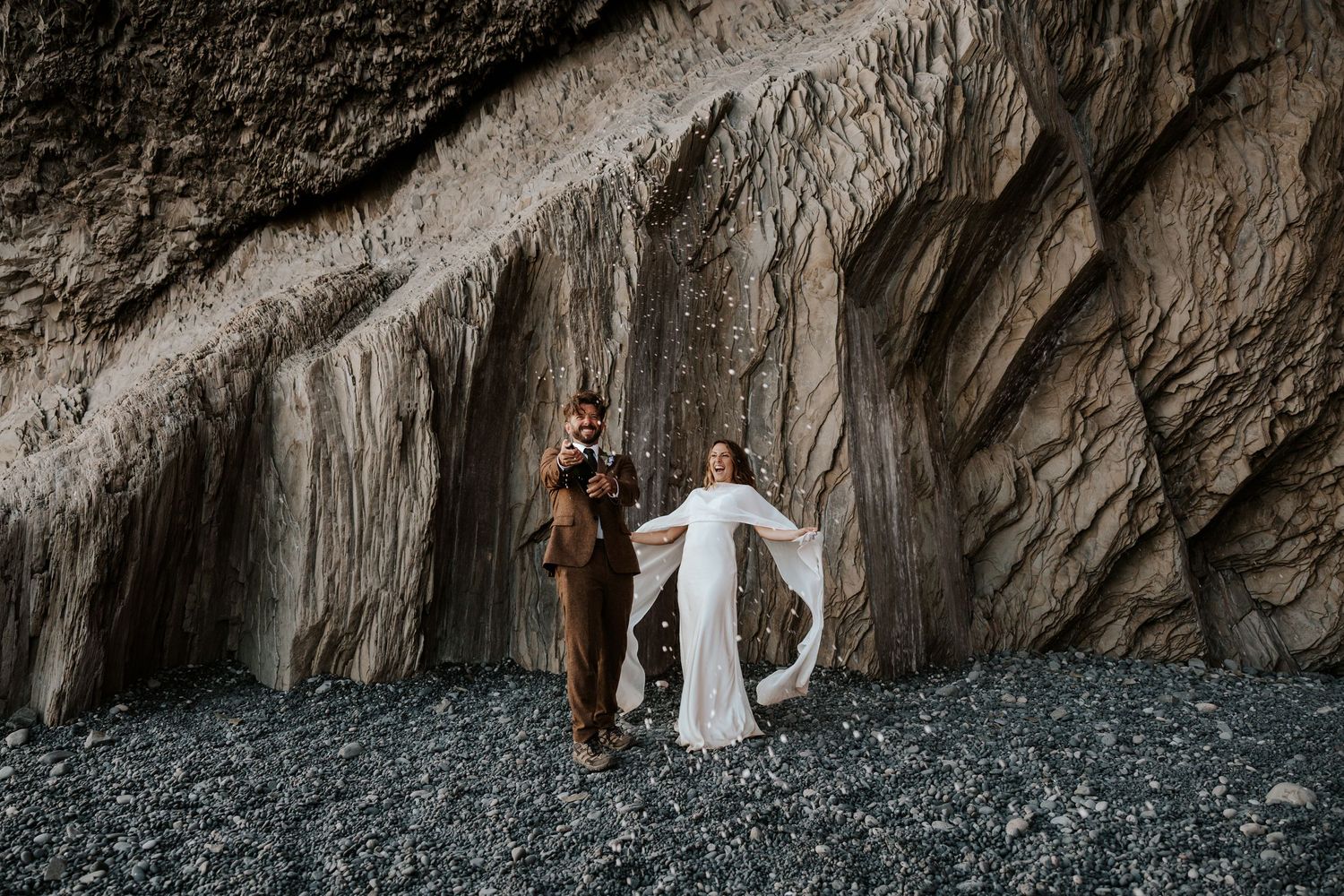 bride and groom popping champagne at Reynisfjara Beach in Iceland after their ceremony on their elopement day