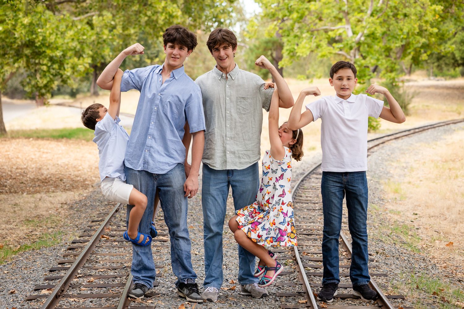 Cousins do a muscle pose with the younger cousins hanging on the muscles of the teens