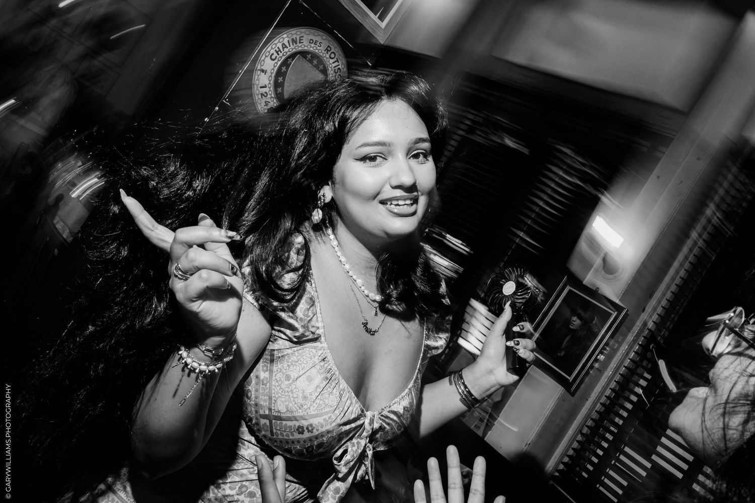 Black and white photo of a smiling woman in a corset costume holding a prop at a themed event.