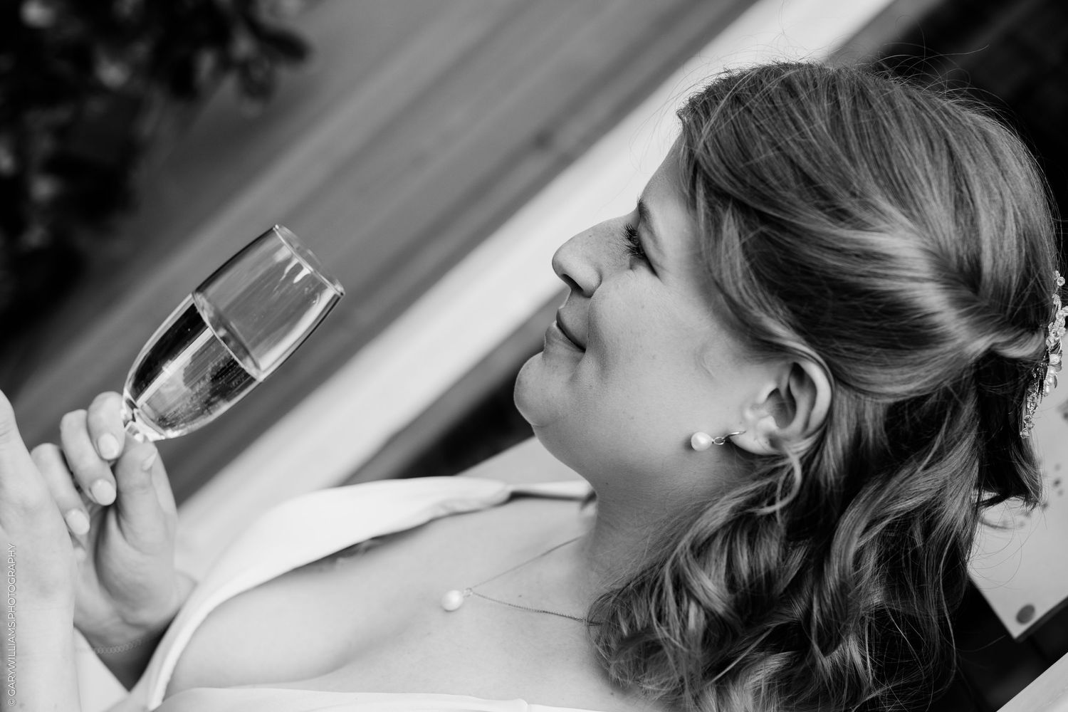 Bride smiling and holding a champagne flute in a black and white wedding photo.