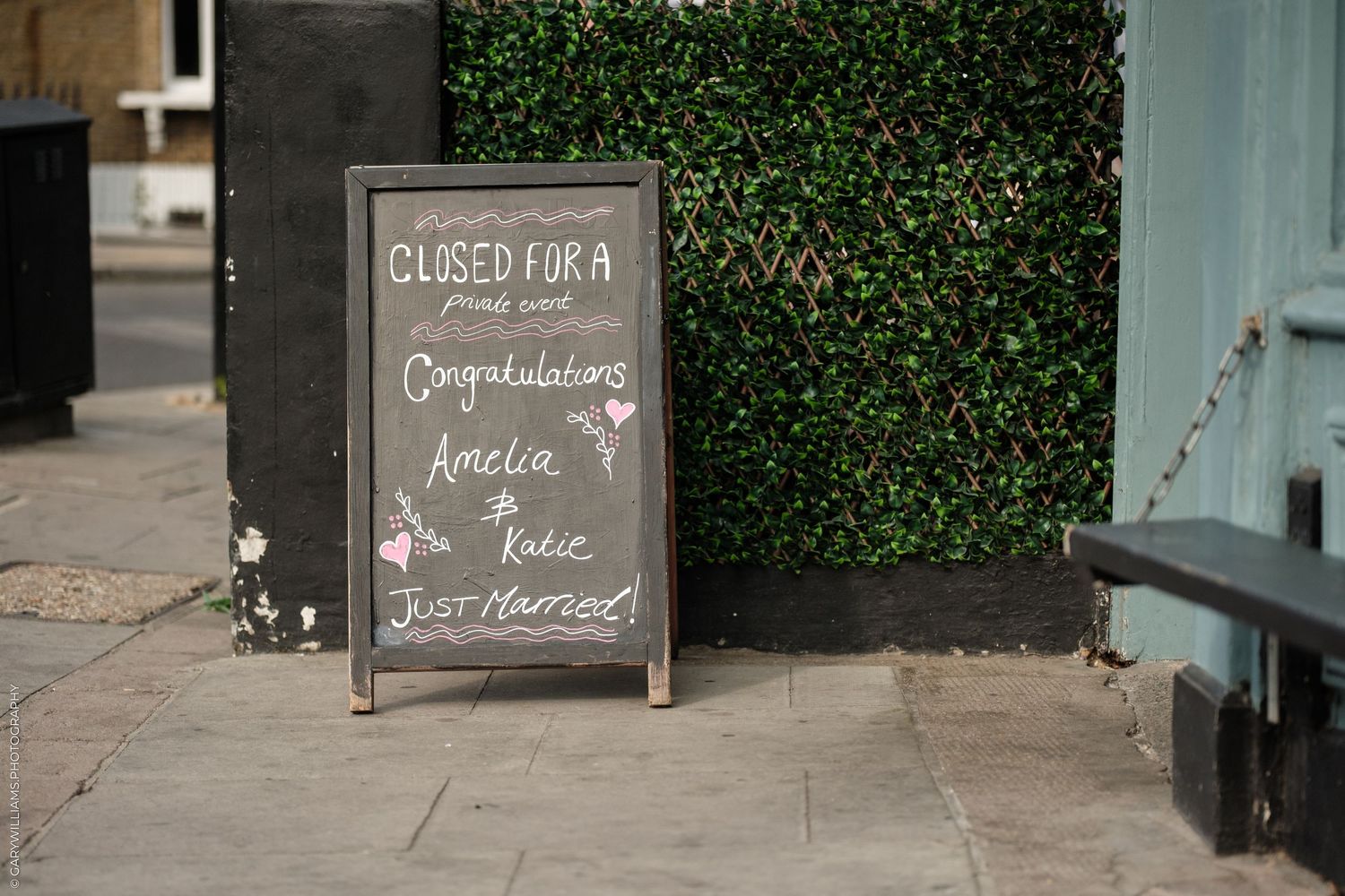 Chalkboard sign outside a restaurant closed for a private event congratulating Amelia and Katie, just married.