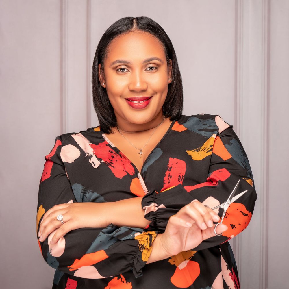 Professional portrait of a person wearing a floral print dress against a gray background.