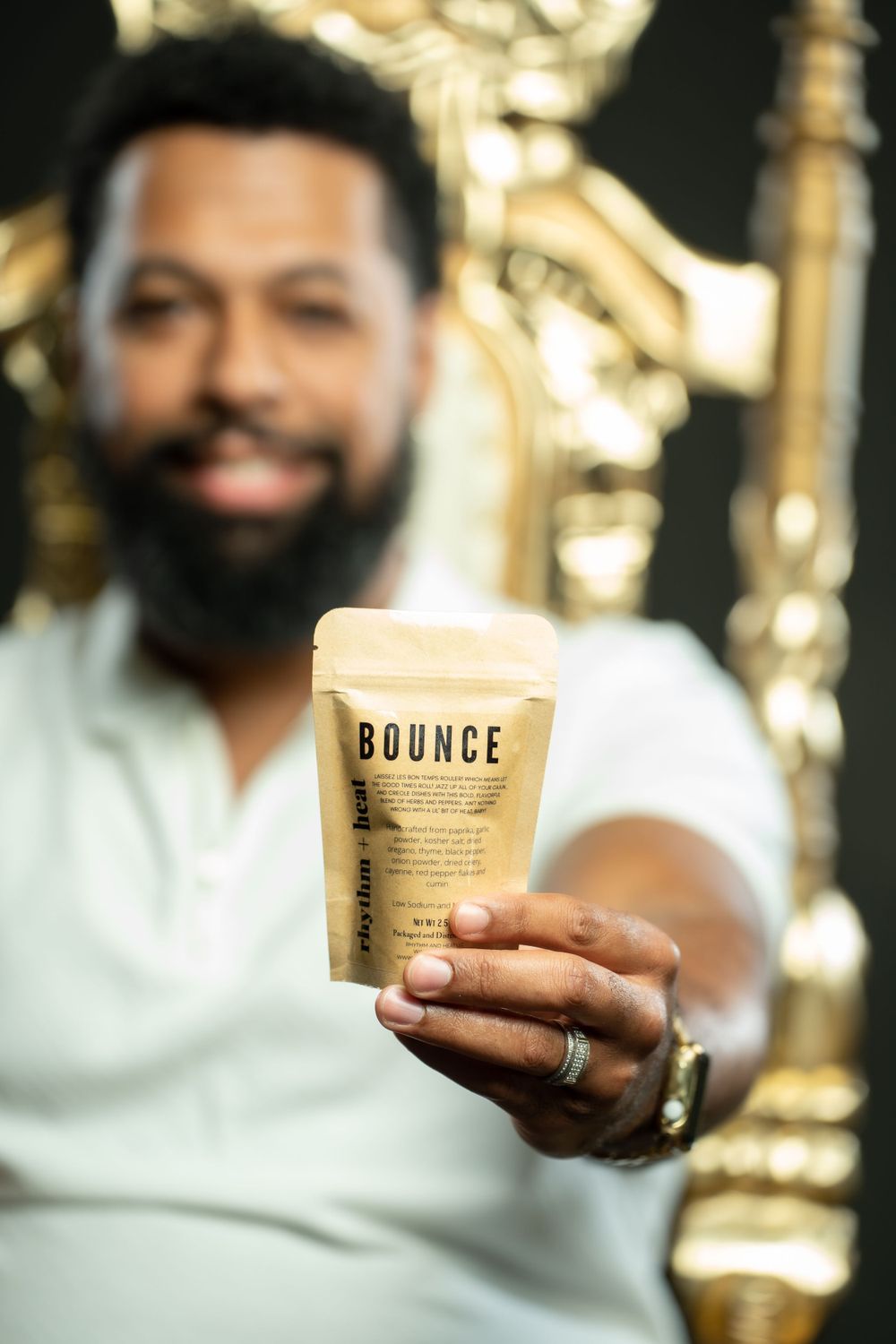 Hand holding a Bounce branded drink cup against golden decorative background.