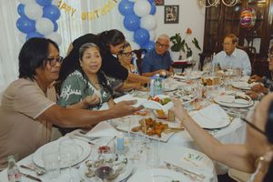 Family and friends gathered around a decorated dining table enjoying food at a birthday party.